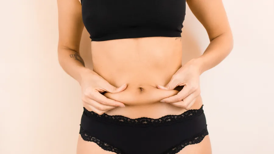 Mujer evaluando su abdomen tras una cirugía estética. Especialista en masajes postoperatorios en Barcelona para reducir inflamación y mejorar resultados.