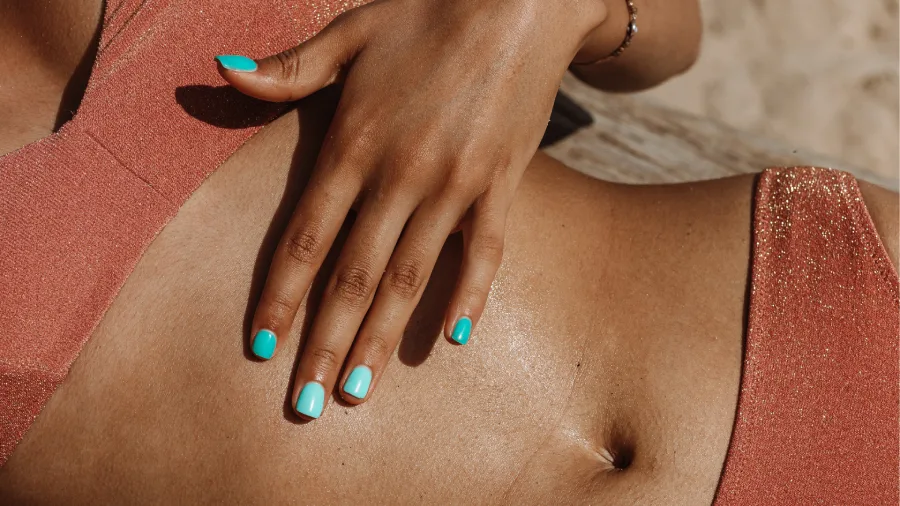 Mano femenina sobre abdomen plano y tonificado gracias al método Thais Leon