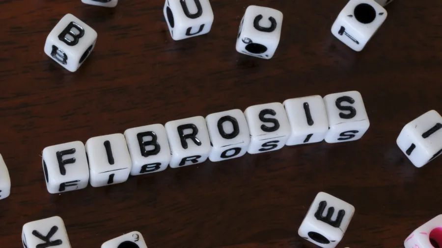 Dados con letras que forman la palabra "fibrosis", representando una de las complicaciones tratadas por un especialista en masajes postoperatorios en Barcelona.