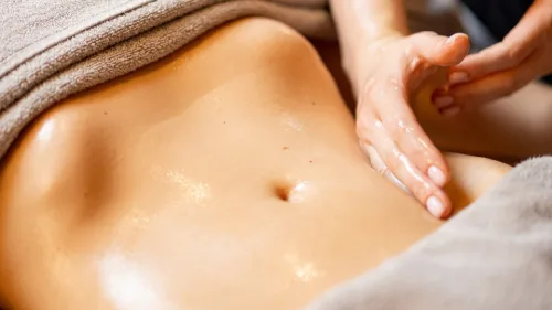 Especialista en masajes postoperatorios en Barcelona aplicando técnica de drenaje linfático en el abdomen de un paciente para mejorar la recuperación